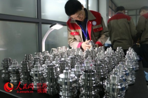 数控项目比赛负责人在观看选手制作的工件。