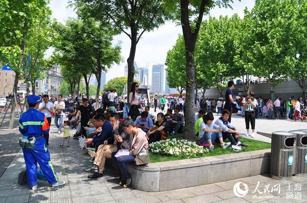 5月1日中午,上海外滩,28℃的高温天,不少游客踩进路边的绿化带休息。(轩召强摄)