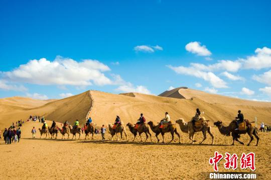 今年“五一”小长假,国际旅游名城敦煌再掀旅游高潮。图为5月1日,游客骑上骆驼欣赏鸣沙山大漠风光。 王斌银 摄