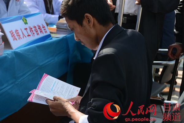 残疾人正在义诊现场阅读资料（周芳霞 摄）