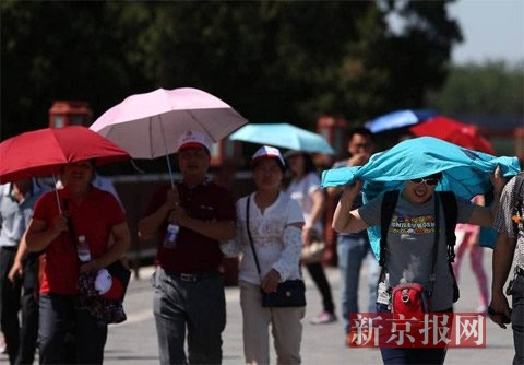 游客打伞或用衣服遮阳。新京报记者 薛珺 摄