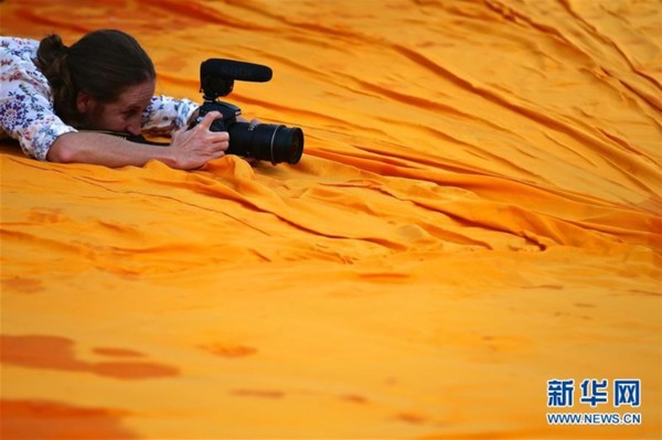 　　6月16日，在意大利伊塞奥湖，一名女士趴在“浮桥”装置艺术上拍摄照片。