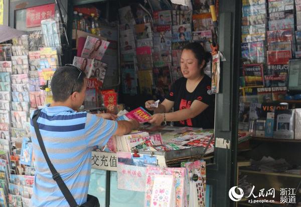 一名游客上前购买杭州地图，冯兰在找零钱之余还不忘向其介绍杭州的风土人情。