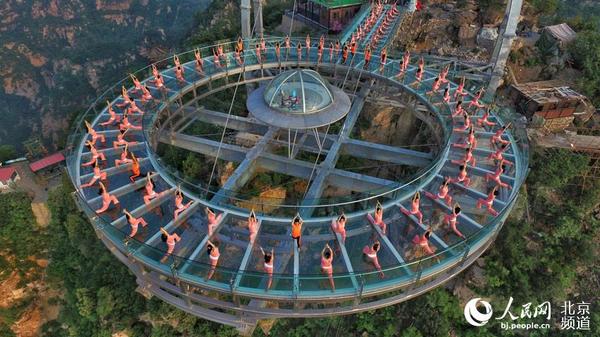 伴着清晨的旭日，瑜珈爱好者在玻璃观景台上练起了瑜珈。