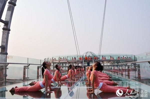 伴着清晨的旭日，瑜珈爱好者在玻璃观景台上练起了瑜珈。人民网尹星云 摄