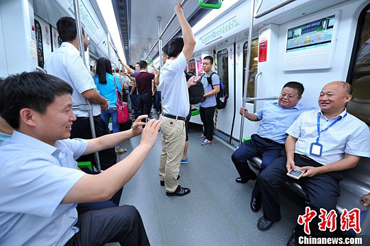 图为体验首趟地铁列车的民众在车厢内拍照留念。中新社记者 胡雁 摄