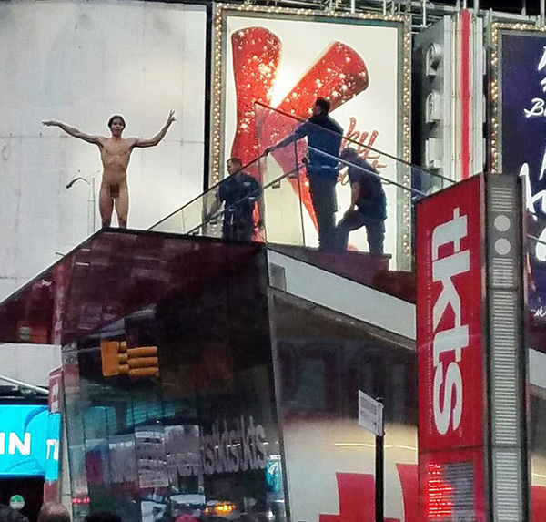 恰逢上班高峰期，这名裸体男子爬上纽约时代广场TKTS百老汇售票亭上面的平台，大喊大叫。（网页截图）