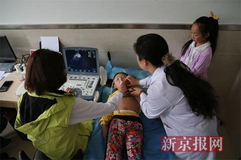 专家在为当地先心病疑似患儿检查。新京报记者 薛珺 摄