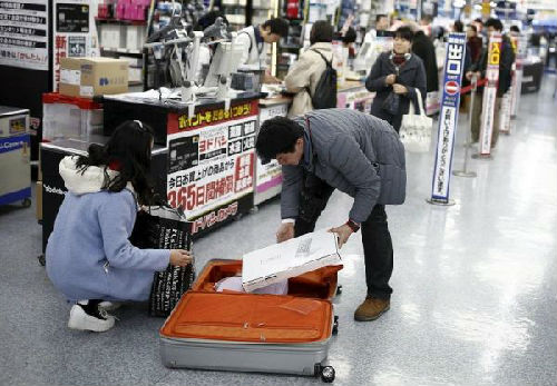 中国游客赴日“爆买”引发热议。图为中国游客在东京一家商场中购物后装箱。（图片来源：路透社）