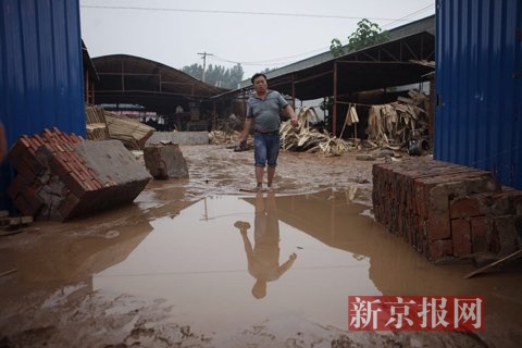 7月23日，桥东板厂门口，梓阳爸爸张苏辉从灾后工厂里走出来。新京报记者王嘉宁摄