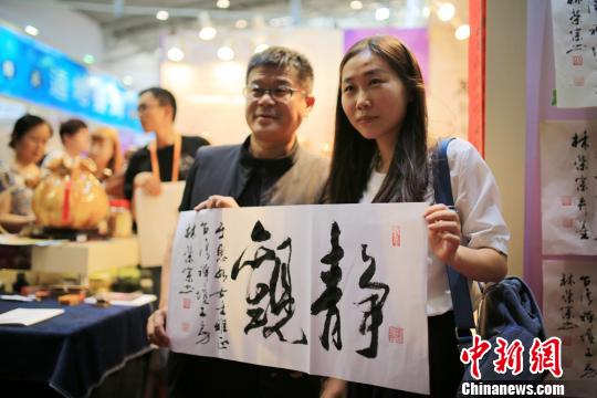 参展客商与台湾工艺书法大师林荣宗先生合影。　年磊　摄