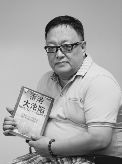 刘深在展示所著《香港大沦陷》一书。新华社发