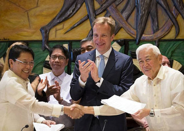 　　8月26日，挪威首都奥斯陆，菲律宾政府代表团团长杜雷萨（左）与菲律宾全国民主阵线代表团团长贾兰多尼在停火协议签字仪式上握手，挪威外交大臣博尔格·布伦德（中）鼓掌祝贺。（图片来源：新华/美联）