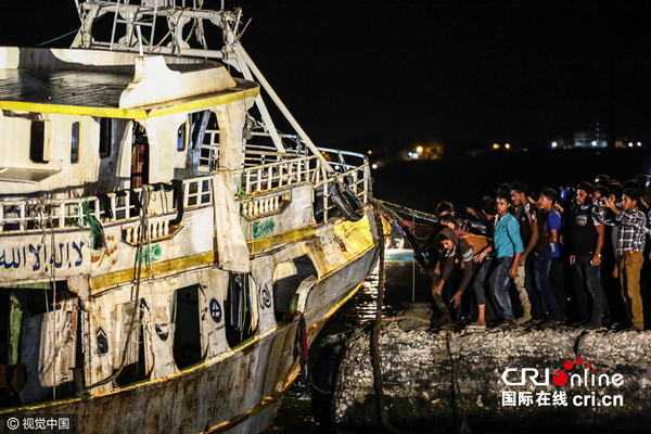 　　当地时间2016年9月27日，埃及罗塞塔，埃及海军将倾覆移民船拖至岸边。根据埃及军方数据，该移民船上共载至少365名移民，在前往意大利途中倾覆，其中163人获救。图片来源：视觉中国