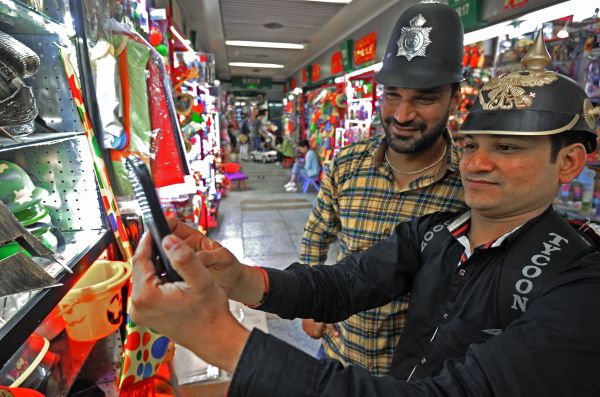 资料图片：两位印度客商人在义乌中国小商品城试戴仿古头盔（4月3日摄）。新华社记者 谭进 摄