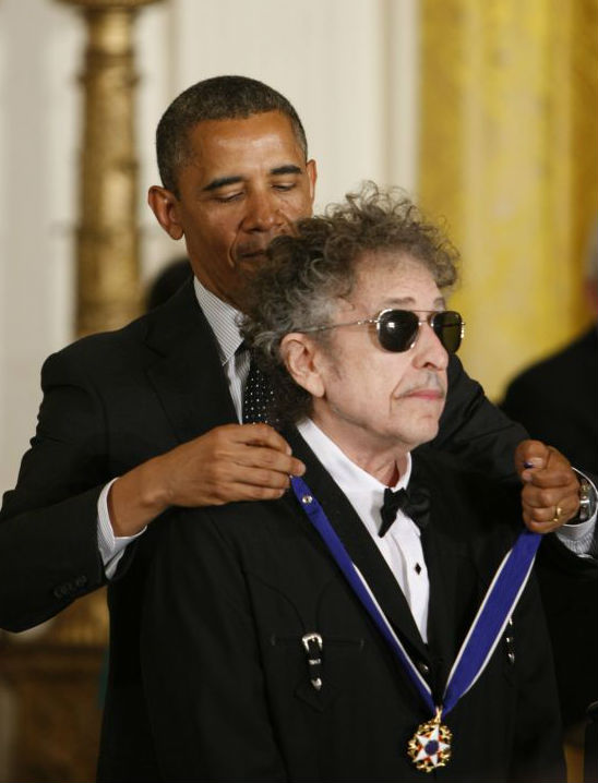 资料图片：2012年5月29日，美国总统奥巴马（上）在白宫举行的颁奖典礼上为流行歌手鲍勃·迪伦佩戴自由勋章。（新华社发）