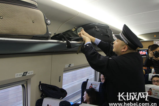 石家庄乘警支队乘警在高铁上为旅客演示行李存放规范。韩晓寒 摄