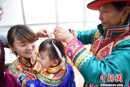 图为长辈将羊毛绑在孩童头发上，寓意孩童头发浓密。　武雪峰摄