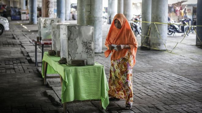 An Indonesian woman casts her vote at a polling station under a highway bridge in Jakarta, Indonesia, 19 April 2017