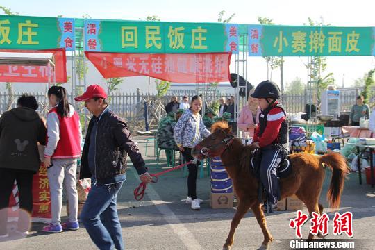 图为小朋友骑着小矮马在展销区内穿过。 袁晶 摄 图为小朋友骑着小矮马在展销区内穿过。 袁晶 摄