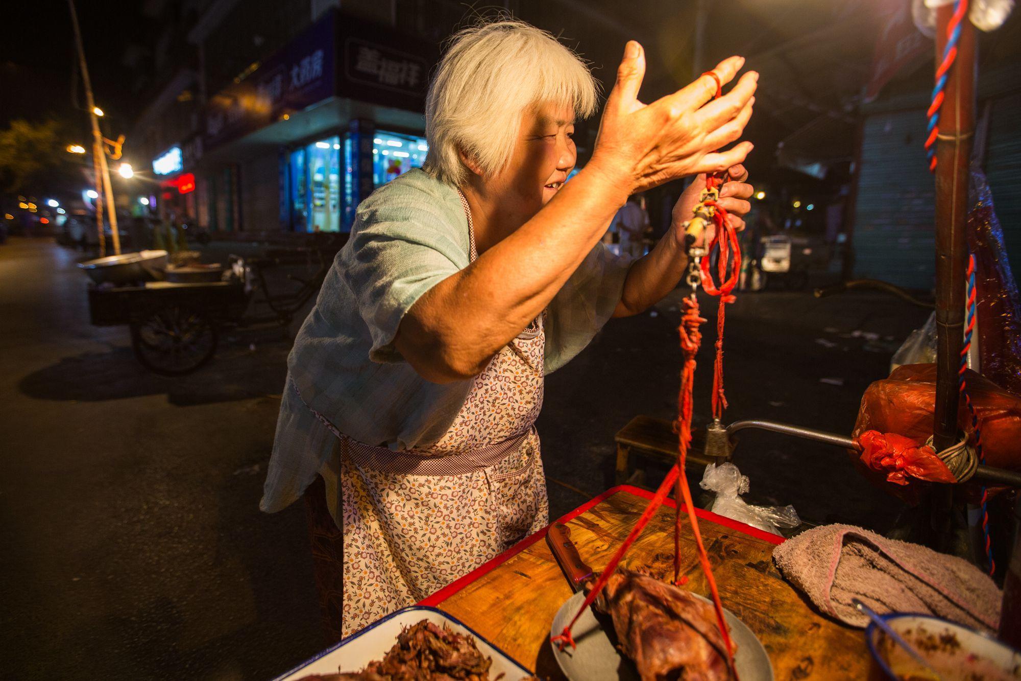 银发老太深夜摆摊卖中药狗肉 剩肉喂狗