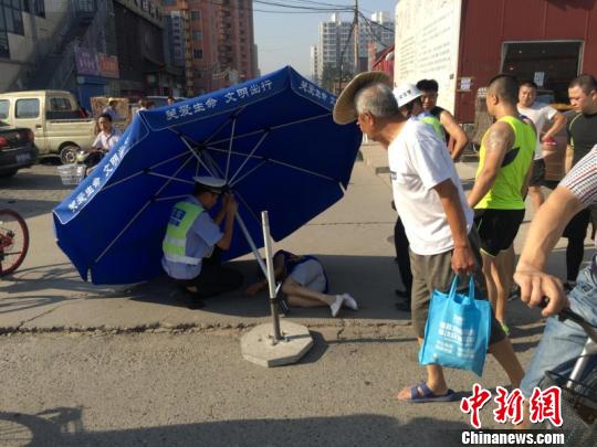 等待急救车到来前，交警查看老人伤情。　宋瑞摄