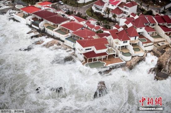当地时间9月6日，飓风“艾尔玛”过境圣马丁岛后，岛上一片狼藉。海边的几栋房屋如“孤岛”般被大浪包围。