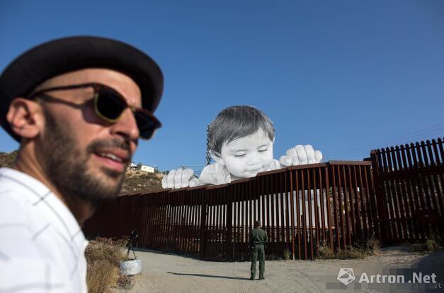 艺术家在美墨边境线创作萌娃扒隔离墙张望