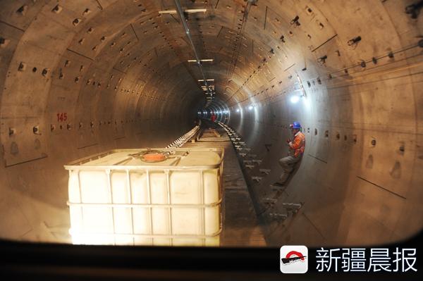 新疆晨报讯(文/记者 许倩 图/首席记者 张万德)预计到10月初,乌市地铁1号线铁路局至国际机场段的双向正线(即运送乘客的线路)轨道就可以全部贯通了。这是9月13日,新疆晨报记者从乌鲁木齐地铁1号线工程轨道安装工程02标段项目部了解到的消息。 当天,新疆晨报记者在城北主干道轨道安装工程02标段的轨排铺装现场看到,圆拱形的隧道内壁都是光滑的混凝土结构,一榀(pn)一榀的轨排依次连接展开。小型龙门吊把轨排吊装到位后,工人们在按照设计高度、弯度将轨排固定起来即可。 据悉,现在该标段左线(铁路局至国际机场)12