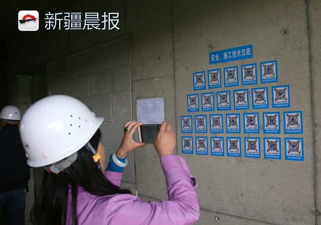 参观人员正扫描乌市天山牧歌二期统建房施工现场的二维码，了解现场施工信息。