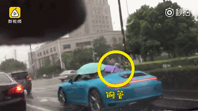 男子开保时捷敞篷跑车打雨伞 冒雨前行就为了一个钢管
