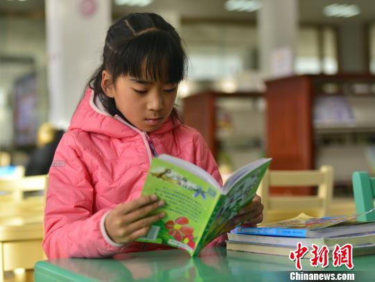 图为在图书馆阅读绘本的西藏小学生次曲。　周文元 摄