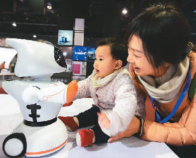 2017年11月23日，在中国义乌国际装备博览会上，一对母子与一台早教型机器人互动。 龚献明摄(人民视觉)