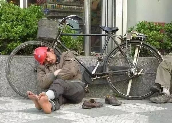 在外找活干的农民工,光着脚丫,靠在自行车上睡着了.