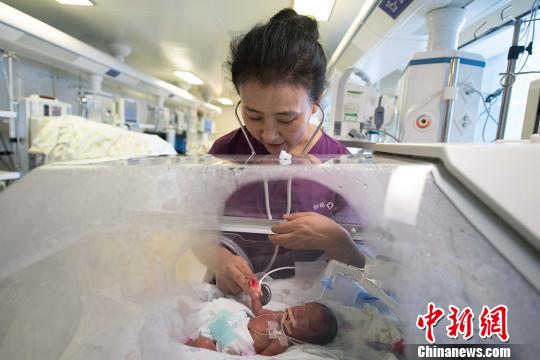 图为山西省儿童医院新生儿重症医学科主任冀�フ�在照顾出生仅10天的小涛。　韦亮摄