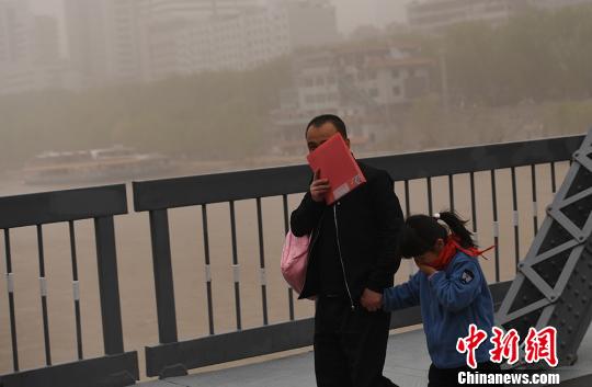 图为一对父女在风沙中出行。　杨艳敏　摄