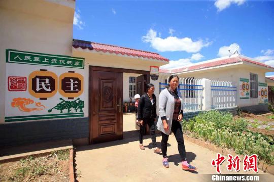 两名彝族妇女从金山村安置点的新家走出　王磊　摄