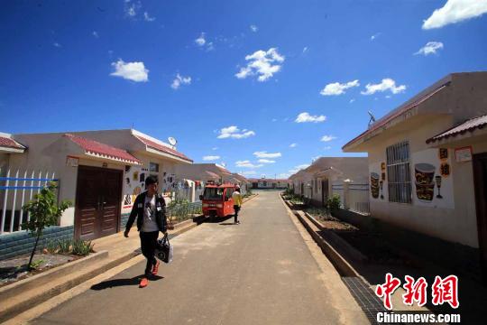 一名彝族青年走在整洁的金山村安置点街道上　王磊　摄