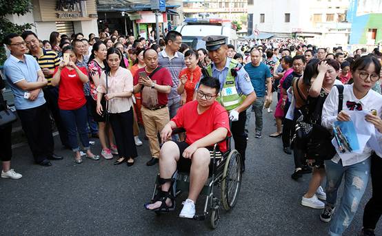 江北18中，警察护送坐轮椅的考生进考场。