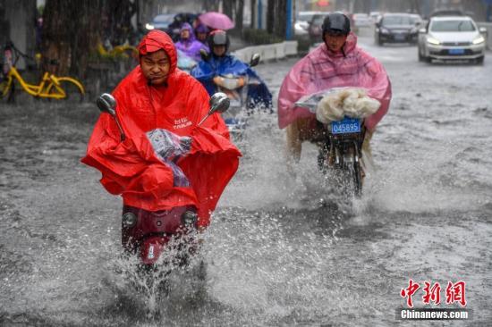资料图：民众冒雨出行。骆云飞 摄