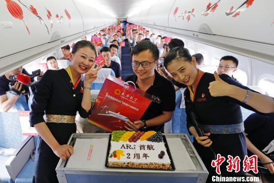 成都航空乘务员与第10万名乘客在ARJ21支线客机客舱内合影留念。　殷立勤 摄