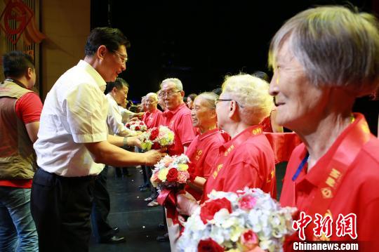 柳州市委书记郑俊康给1958年进入柳钢工作的代表献花。 朱柳融 摄 柳州市委书记郑俊康给1958年进入柳钢工作的代表献花。 朱柳融 摄