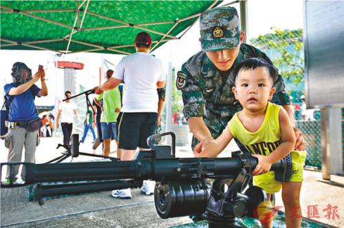 有儿童在士兵协助下参与体验模拟射击。图片来源:香港《文汇报》记者莫雪芝/摄 有儿童在士兵协助下参与体验模拟射击。图片来源:香港《文汇报》记者莫雪芝/摄
