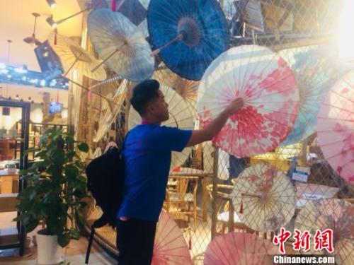 香港青年欣赏形式多样的油纸伞。　郭其钰 摄