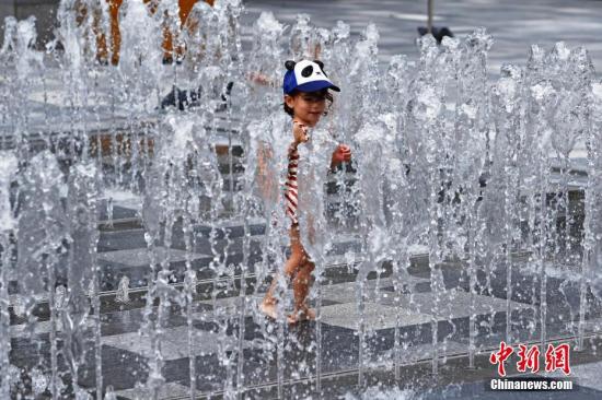 资料图：上海持续高温，孩子在喷水池里嬉水。 殷立勤 摄