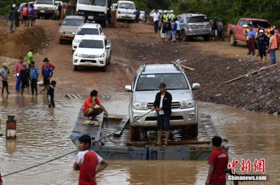 资料图：当地时间2018年7月25日，老挝阿速坡省Sanamxai，色贡河水位上涨，民众使用简易木筏过河。老挝南部阿速坡省一水电站23号晚发生溃坝事故，已导致数人死亡、数百人失踪。附近6个村庄被淹没，其中两个村庄受灾最为严重，超过6600人因洪水无家可归。