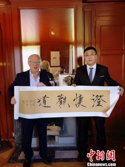 以创作“中国红”主题作品闻名的中国艺术家崔景哲(右一)向奥林匹克博物馆赠送其书法作品 周子佳 摄