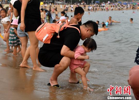 家长带小朋友在海滩上游玩。　吕明 摄