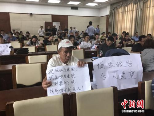 发布会中，一名家属手举标语。 冷昊阳摄