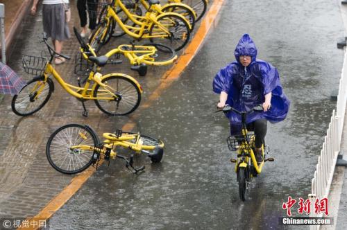 资料图：北京迎来强降雨，街头民众冒雨出行。图片来源：视觉中国